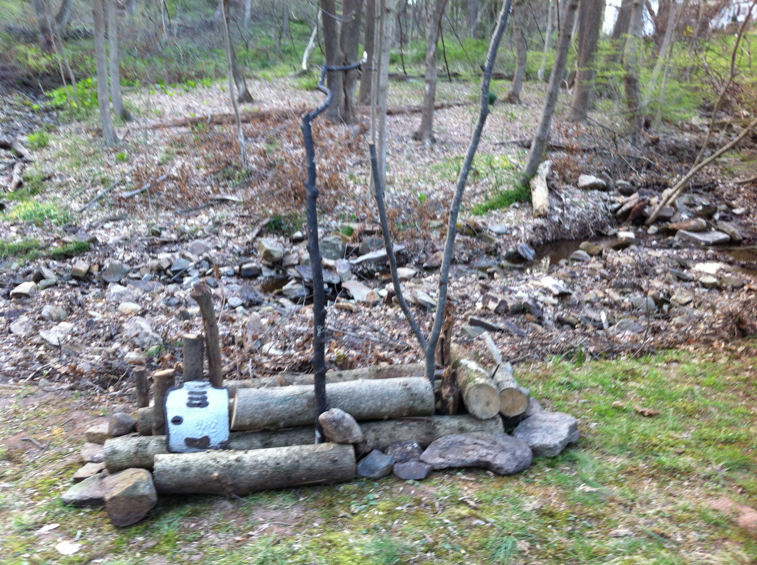 A metal scrap with a face on it, on a woodpile.